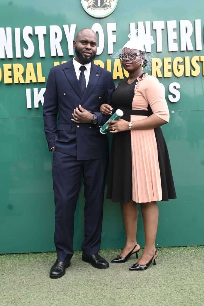 Formal couple posing in front of a green Ministry of Interior marriage registry sign.