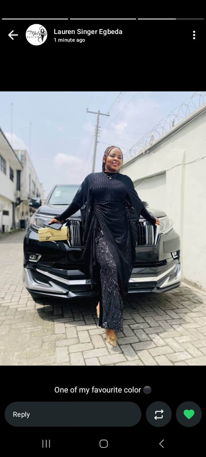 Smiling woman in elegant black attire posing in front of a black luxury SUV.
